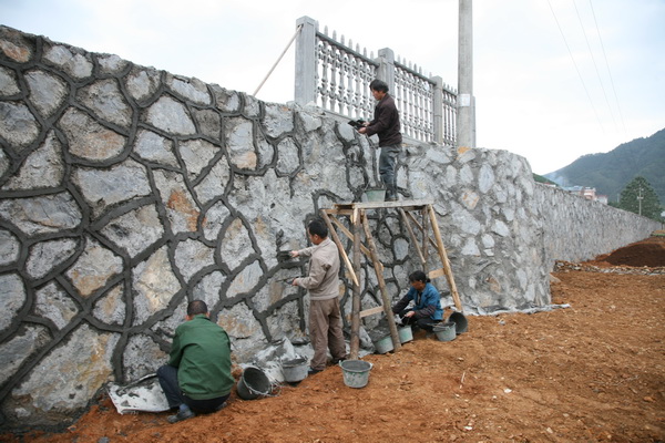 11月2日,施工人员在开化县华埠中学建设的校安工程项目挡土墙上抹水泥