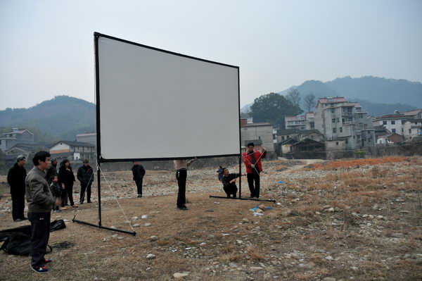 搭建放映幕布放映员在调试机器河滩上的露天电影让村民们看得津津有味